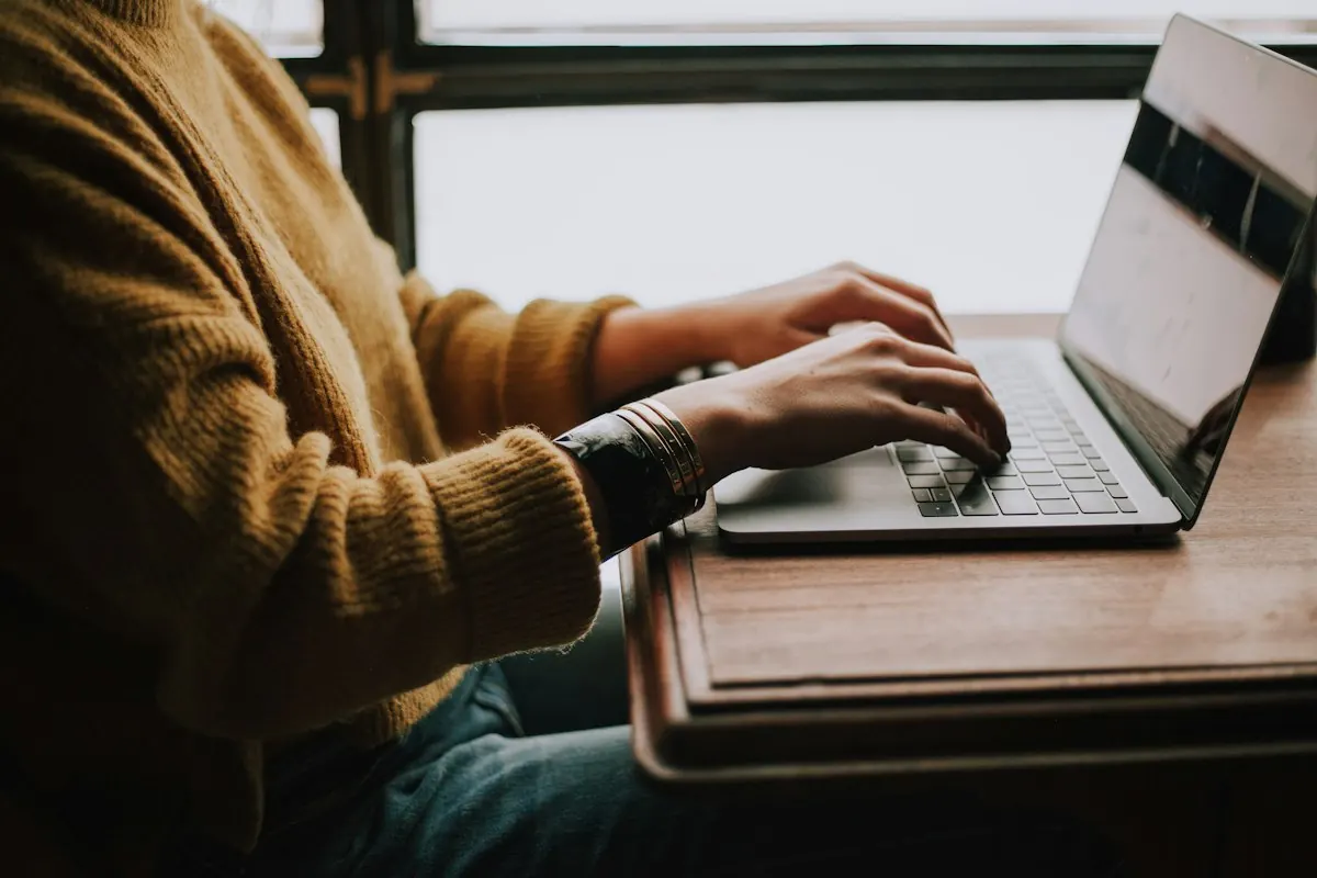 Osoba przeglądająca media społecznościowe na telefonie przy laptopie